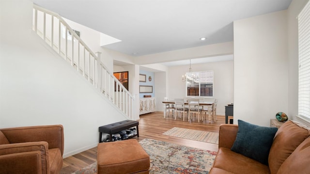 living area featuring stairs, an inviting chandelier, wood finished floors, and baseboards