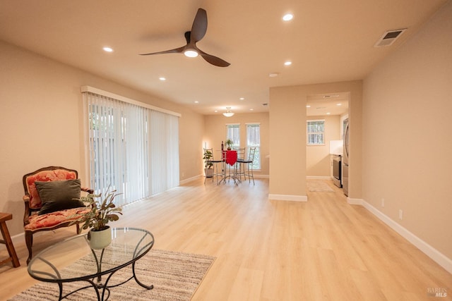 living area featuring light wood-type flooring and ceiling fan