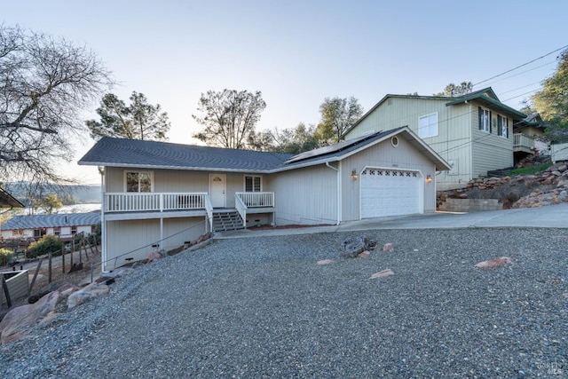 view of front of house featuring driveway, an attached garage, and solar panels