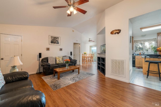 living room featuring a healthy amount of sunlight, visible vents, vaulted ceiling, and dark wood-style flooring