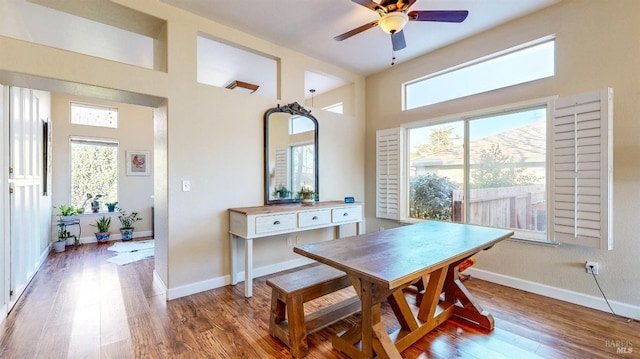 dining area featuring ceiling fan, a high ceiling, wood finished floors, and baseboards