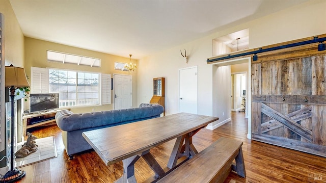 dining room with a barn door, a notable chandelier, and wood finished floors