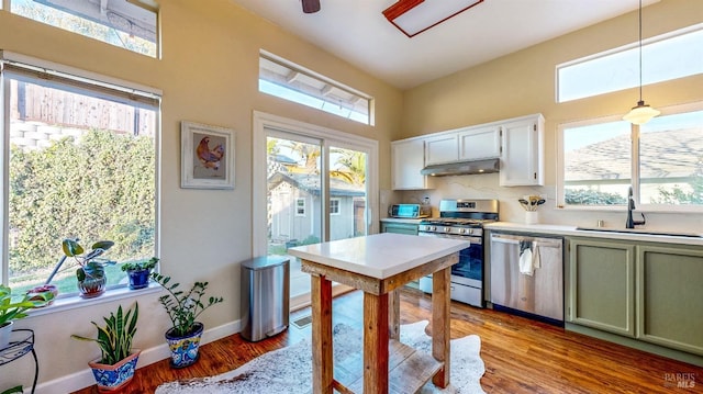 kitchen with a sink, light countertops, light wood-style floors, under cabinet range hood, and stainless steel appliances