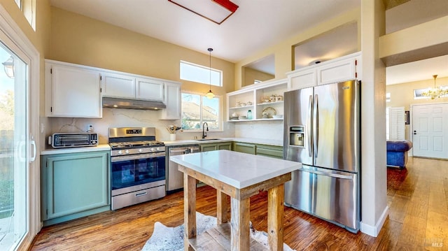 kitchen with pendant lighting, sink, hardwood / wood-style flooring, white cabinetry, and stainless steel appliances