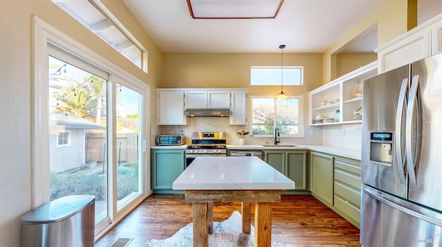 kitchen with pendant lighting, dark wood-type flooring, backsplash, stainless steel appliances, and green cabinetry