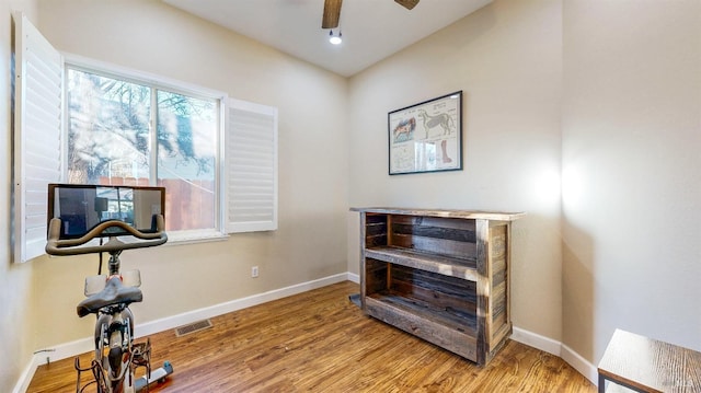 exercise area featuring wood finished floors, baseboards, a ceiling fan, and visible vents