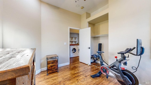 workout area featuring washing machine and dryer, baseboards, and wood finished floors