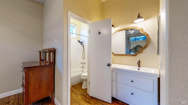 full bathroom with ceiling fan, shower / bathtub combination, vanity, toilet, and wood finished floors