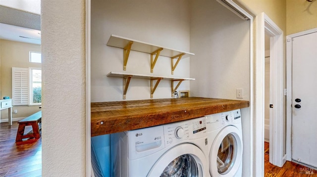 clothes washing area with washer and dryer and wood finished floors