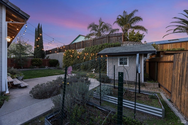 yard at dusk featuring a patio and an outbuilding