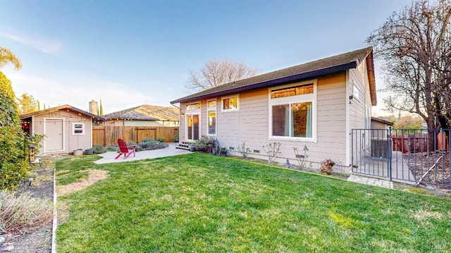 rear view of property featuring an outdoor structure, a patio area, a fenced backyard, a lawn, and a storage unit