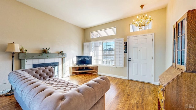 living room featuring a tiled fireplace, hardwood / wood-style floors, and an inviting chandelier