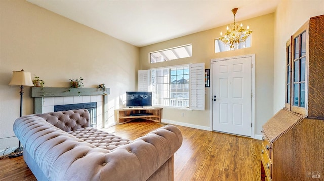 living room with baseboards, a notable chandelier, wood finished floors, and a fireplace