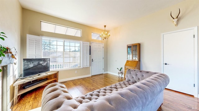 living area with baseboards, an inviting chandelier, and wood finished floors