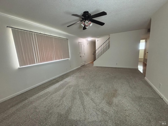 spare room featuring ceiling fan, carpet, and a textured ceiling