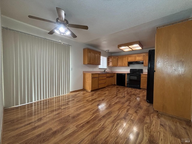 kitchen featuring dark hardwood / wood-style floors, sink, a textured ceiling, and black appliances