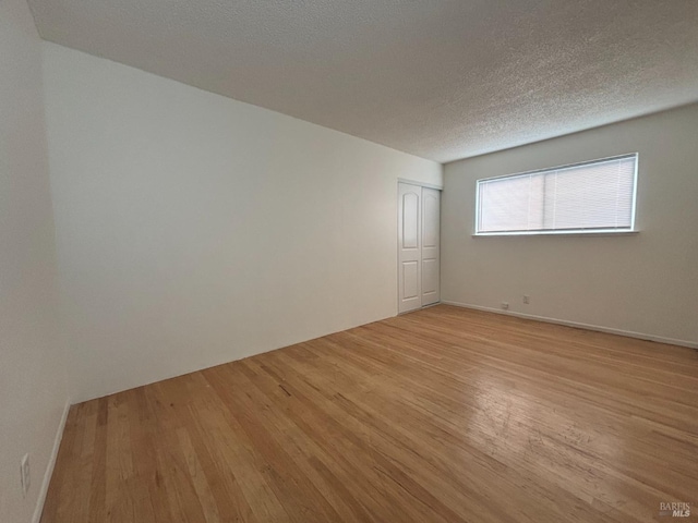 unfurnished room featuring a textured ceiling and light wood-type flooring