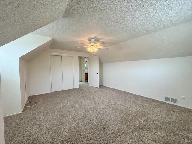 bonus room featuring ceiling fan, lofted ceiling, carpet, and a textured ceiling