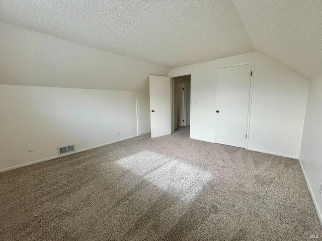 additional living space featuring lofted ceiling, carpet flooring, and a textured ceiling