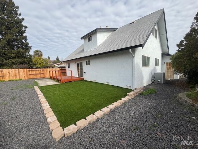 back of property featuring a wooden deck, central AC, and a lawn