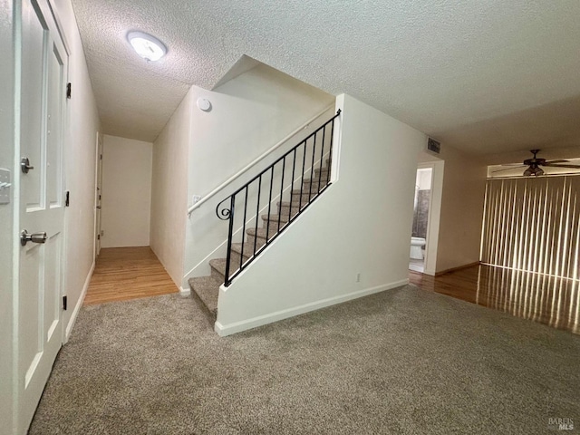 carpeted entryway featuring ceiling fan and a textured ceiling