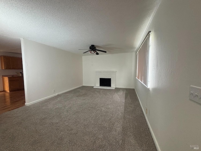 unfurnished living room with ceiling fan, carpet flooring, and a textured ceiling