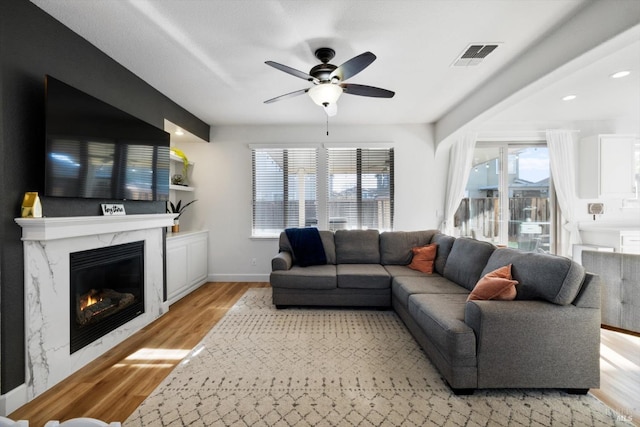 living room with light hardwood / wood-style flooring, a fireplace, and ceiling fan