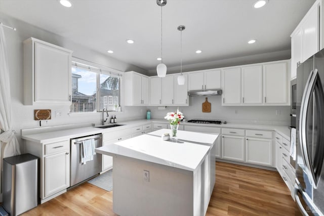 kitchen featuring sink, hanging light fixtures, appliances with stainless steel finishes, a kitchen island, and white cabinets