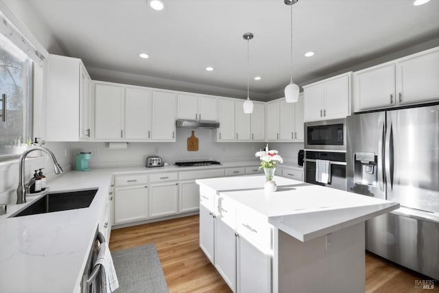 kitchen featuring a kitchen island, appliances with stainless steel finishes, sink, white cabinets, and hanging light fixtures