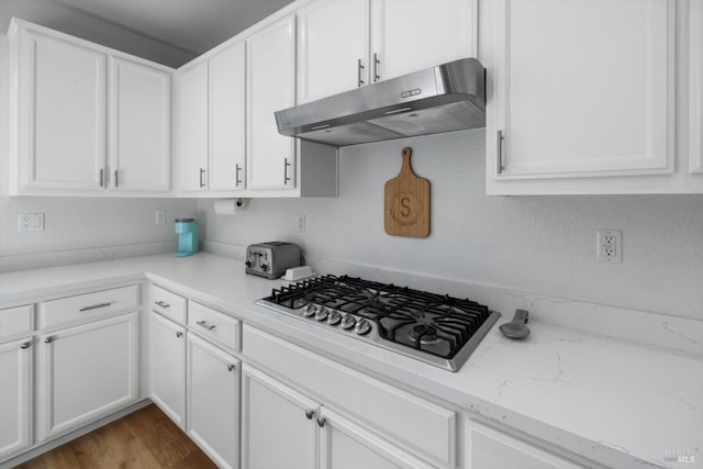 kitchen with white cabinetry, stainless steel gas stovetop, wood-type flooring, and light stone counters