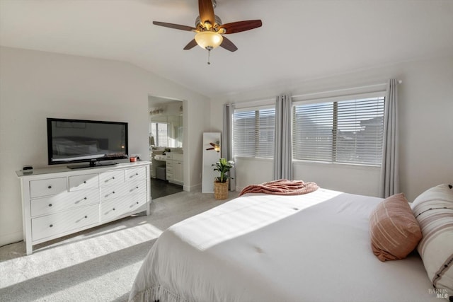 bedroom featuring vaulted ceiling, light colored carpet, ceiling fan, and ensuite bathroom