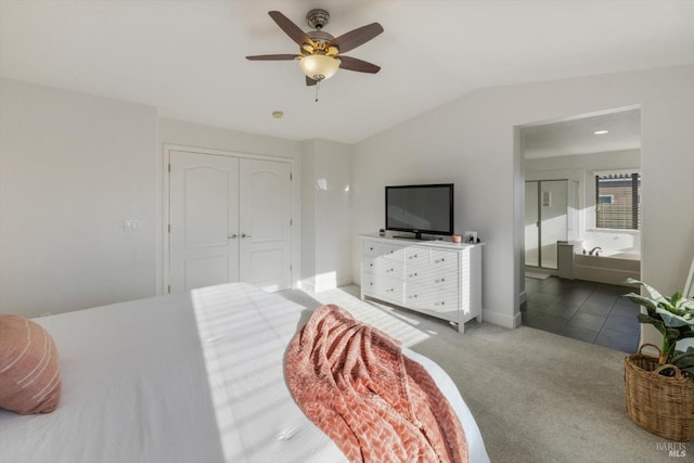 carpeted bedroom featuring lofted ceiling, ensuite bath, ceiling fan, and a closet