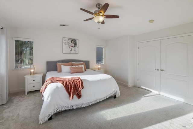 bedroom featuring lofted ceiling, light carpet, ceiling fan, and a closet