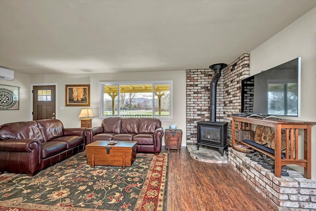 living area with wood finished floors, a wood stove, and a healthy amount of sunlight