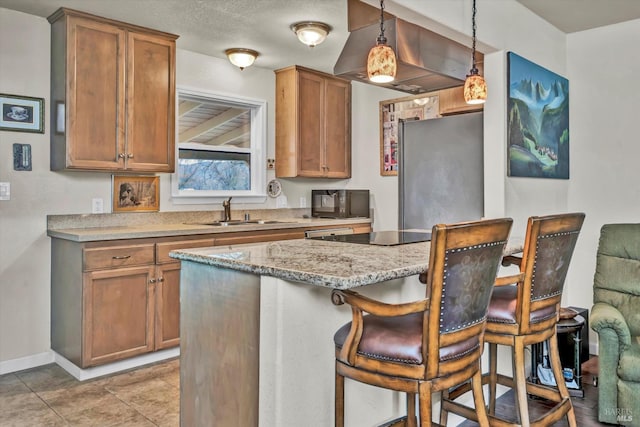 kitchen featuring brown cabinets, hanging light fixtures, a sink, black appliances, and a kitchen bar