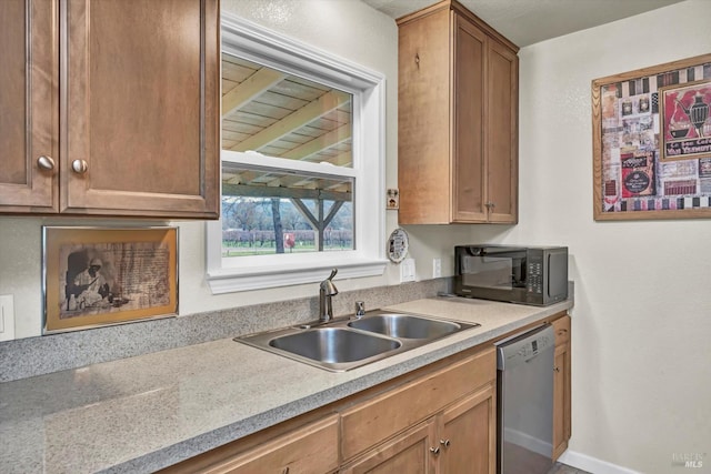 kitchen featuring brown cabinetry, light countertops, stainless steel dishwasher, black microwave, and a sink