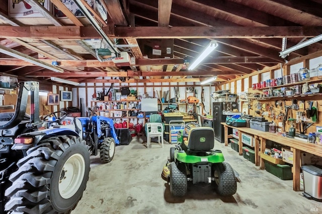 miscellaneous room featuring a garage, unfinished concrete flooring, and a workshop area