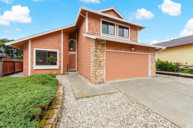 view of front of home featuring a garage, stone siding, driveway, and fence