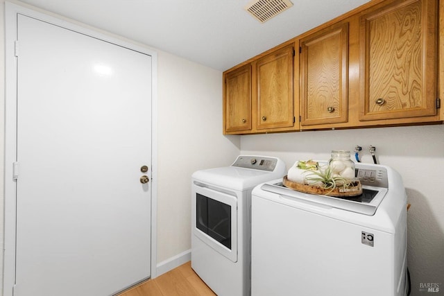 washroom with cabinets, independent washer and dryer, and light hardwood / wood-style floors