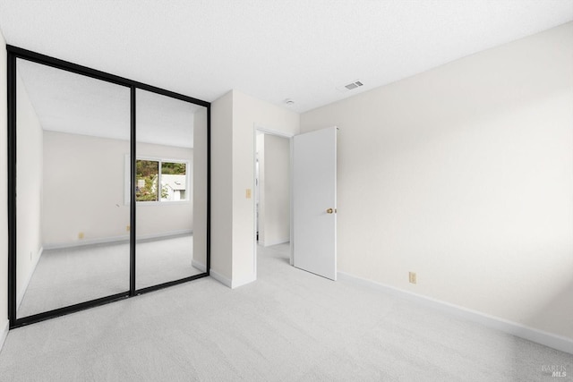 unfurnished bedroom featuring a closet, light carpet, and a textured ceiling