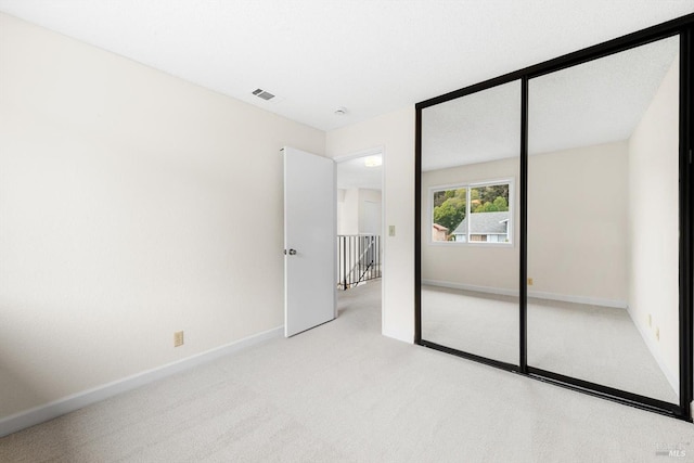 unfurnished bedroom with light carpet and a closet