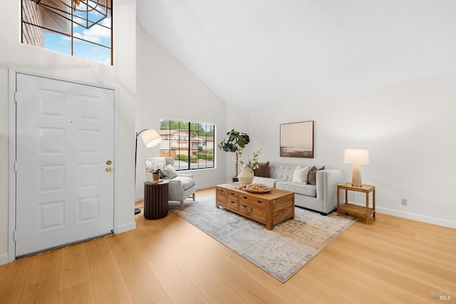 living room with high vaulted ceiling and light wood-type flooring