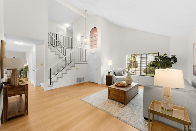 living room with a notable chandelier, high vaulted ceiling, and light wood-type flooring