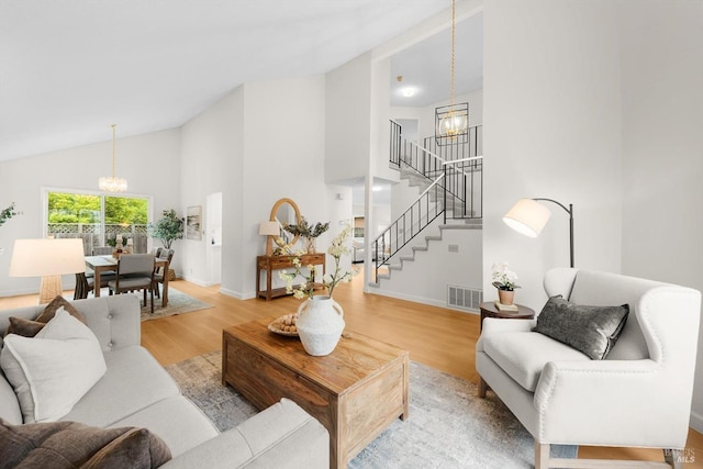 living room featuring an inviting chandelier, high vaulted ceiling, and light hardwood / wood-style flooring