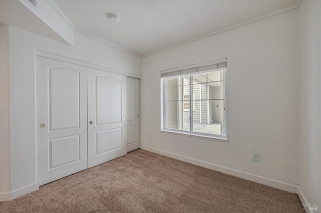 unfurnished bedroom with ornamental molding, light colored carpet, and a closet