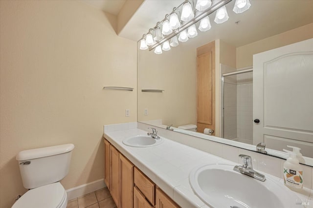 bathroom featuring tile patterned flooring, vanity, a tile shower, and toilet