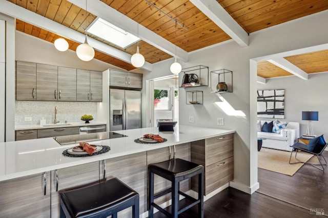 kitchen featuring light countertops, appliances with stainless steel finishes, a peninsula, and a sink