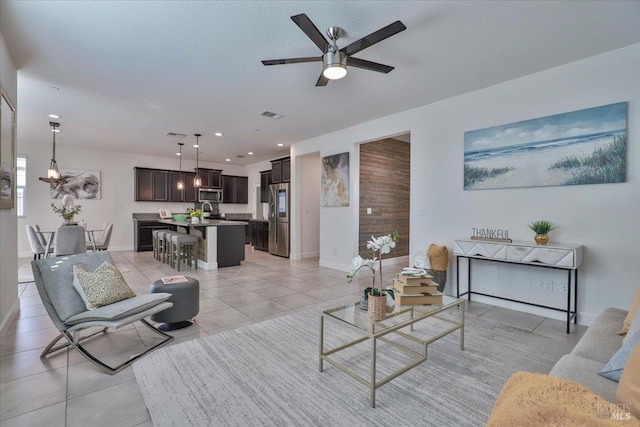 living room with ceiling fan, sink, and light tile patterned floors