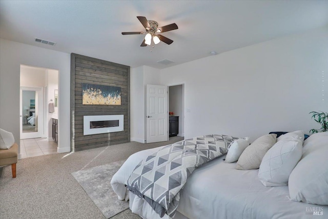 bedroom featuring light carpet, a large fireplace, and ceiling fan