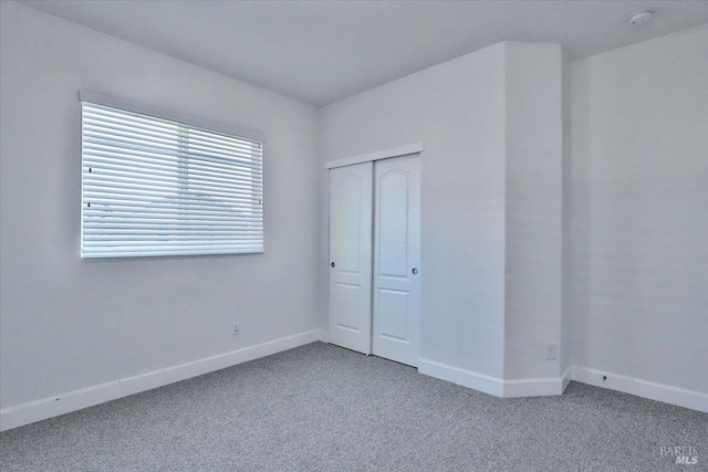 unfurnished bedroom featuring light colored carpet and a closet